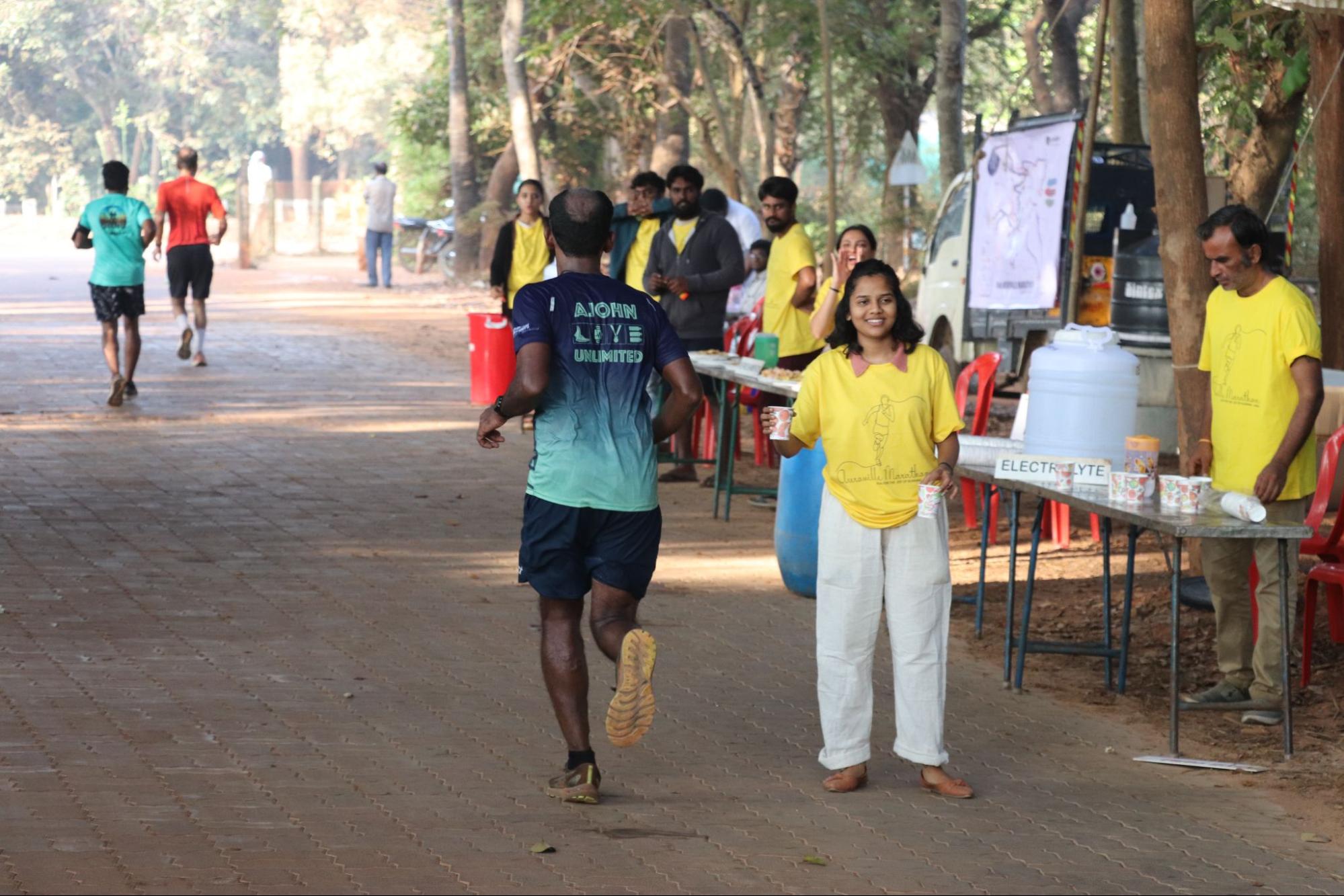 Auroville Marathon runner passing by aid/drink stations.